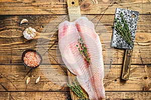 Raw fillet of pangasius fish on a cutting board. Wooden background. Top view