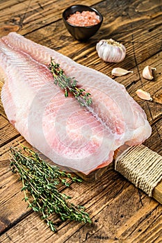 Raw fillet of pangasius fish on a cutting board. Wooden background. Top view