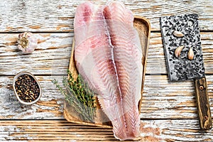 Raw fillet of pangasius fish. White wooden background. Top view