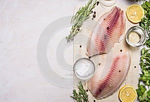 Raw fillet of tilapia with salt, lemon and butter, rosemary herbs, border place for text