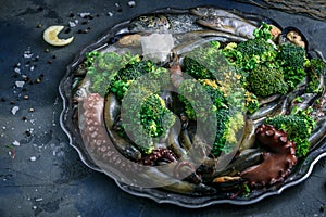 Raw fish, octopus, s.hrimps and mussels on a plate with vegetables