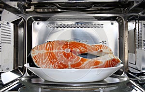 Raw fish in plate defrosting using microwave oven