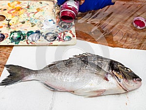 Raw fish and pouring acrylic paint in palette