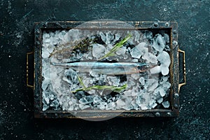 Raw fish saira on ice on a black stone background. Seafood.