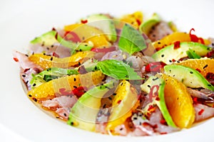 Raw fish salad carpaccio with avocado and orange slices