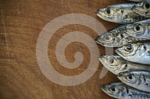 Raw fish (scad) over natural wood background