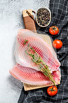 Raw fish tilapia on the cutting Board. Gray background. Top view