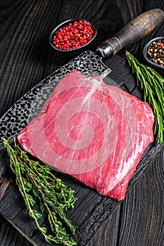 Raw flank or bavette beef meat steak on a wooden cutting board. Black background. Top view