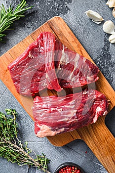 Raw flap steak flank cutHanger steak, bistro steak, fajita meat, on woods chopping board, with herbs tomatoes peppercorns over photo