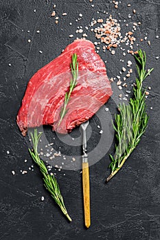 Raw Flat iron steak with rosemary and pink salt. Fresh Marble beef meat black Angus. Black background. Top view