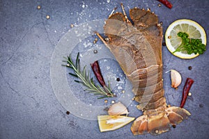 Raw flathead lobster shrimps with herbs and spices, fresh slipper lobster flathead for cooking on dark background in the seafood