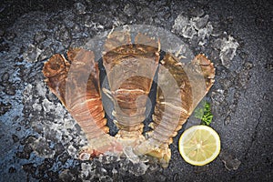 Raw flathead lobster shrimps on ice, fresh slipper lobster flathead for cooking on dark background in the seafood restaurant or