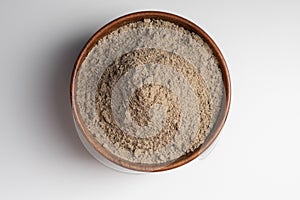 Raw flax seeds flour in a wooden bowl with on white background. Top view.