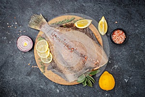 Raw flounder fish flatfish with lemon and spices on a dark background. banner, menu, recipe place for text, top view