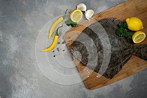 Raw flounder fish with spices. Seafood on a black stone background. Top view.