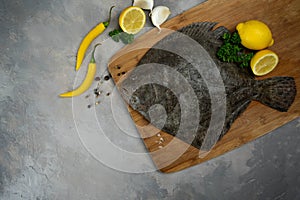 Raw flounder fish with spices. Seafood on a black stone background. Top view.