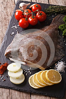 Raw flounder with ingredients on a slate board closeup. Vertical