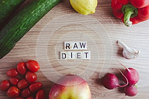 Raw food diet concept. Text from wooden blocks with fresh vegetables and fruits