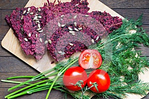 Raw foods. Dry vegan bread loaves from beet and walnut on kitchen board on wooden table