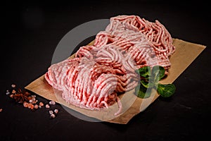 raw forcemeat on craft paper with spices and basil