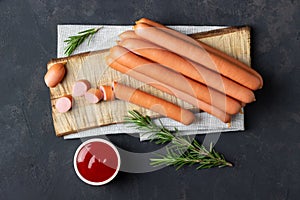 Raw frankfurter sausages with ketchup on cutting board photo