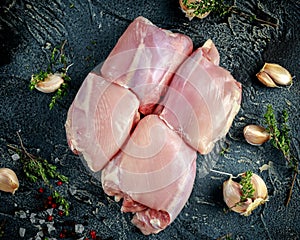 Raw Free range Boneless skinless chicken thighs with thime, garlic, red pepper corns and sea salt flakes on stone table photo