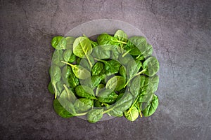 Raw fresh baby spinach leaves in bowl on grey background. Frame made of spinach background. Top view healthy leaf