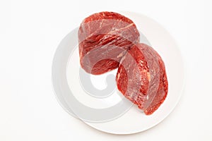 Raw fresh beef meat pieces on white plate, top view