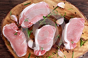 Raw Fresh Boneless Pork Chops with herbs. on wooden board.