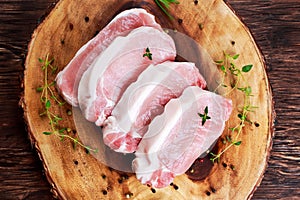 Raw Fresh Boneless Pork Chops with herbs. on wooden board.