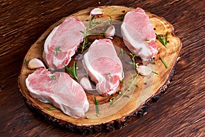 Raw Fresh Boneless Pork Chops with herbs. on wooden board.