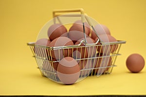 Raw, fresh chicken eggs in a basket. Brown eggs in a basket on a light, yellow background. Copy space