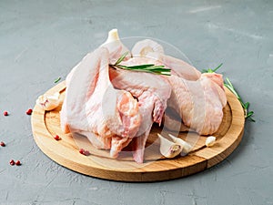 raw fresh chicken wings on wooden board, grey concrete background, side view