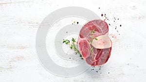 Raw fresh cross cut veal shank with spices and herbs on a white background. Cheese Bif steak Ossbo. Top view.