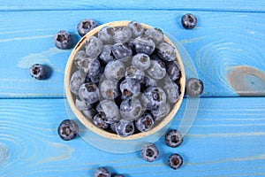 Raw fresh huckleberry in a bowl. Wooden background