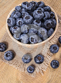 Raw fresh huckleberry in a bowl. Wooden background