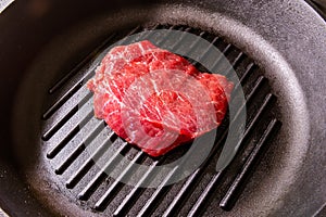 Raw, fresh, juicy marbled meat roast beef is ready to cook, on a grill pan with fluting.