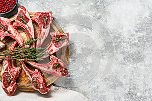 Raw fresh lamb rib chops with salt, pepper and herbs. Gray background. Top view. Copy space