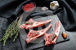 Raw fresh lamb ribs with pepper and rosemary. Organic meat. Black background. Top view