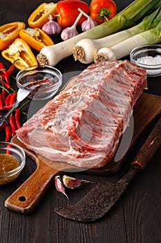 Raw fresh lamb ribs on wooden cutting board on dark background