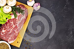 Raw fresh marble meat steak and seasonings on a dark marble background, top view