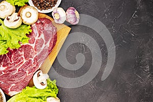 Raw fresh marble meat steak and seasonings on a dark marble background, top view