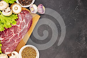 Raw fresh marble meat steak and seasonings on a dark marble background, top view