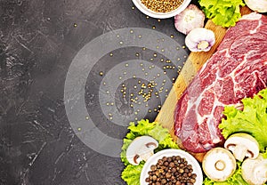 Raw fresh marble meat steak and seasonings on a dark marble background, top view