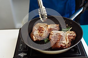 Raw Fresh Marbled Meat Beef on a grill pan ready for cooking. Man cooking beef steaks. Male hands holding a grill pan