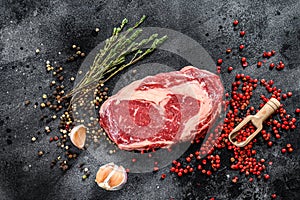 Raw fresh meat Ribeye Steak with seasoning. Rib eye beef steak. black background. top view