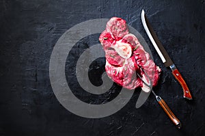 Raw fresh meat steak with cherry tomatoes, hot pepper, garlic, oil and herbs on dark stone, concrete background. Banner.