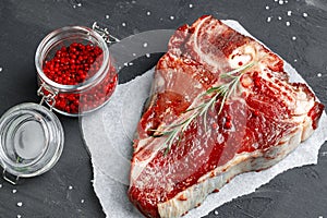 Raw fresh meat t-bone steak with spices on a dark background