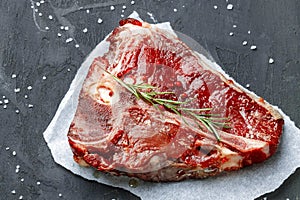 Raw fresh meat t-bone steak with spices on a dark background