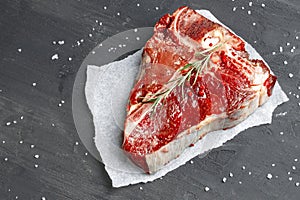 Raw fresh meat t-bone steak with spices on a dark background